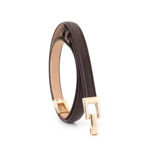 Detail view of women's slim brown leather belt featuring elegant gold metal interlocking buckle.