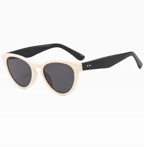 Detalle de gafas de sol ojo de gato retro, montura crema y patillas negras, estilo elegante.