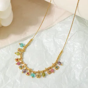 Primer plano detalle del collar de oro con racimo de flores de piedra natural de color.