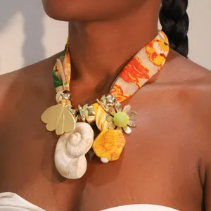 Primer plano del collar tipo pañuelo de seda estampado bohemio con dijes de concha y mariposa