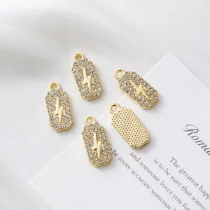 Detailed view of gold lightning bolt charms with rhinestone pave and textured back