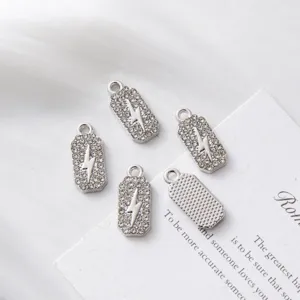 Macro view of silver lightning bolt rectangular charms with pavé set white stones for DIY