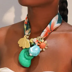Detalle del collar de pañuelo de seda bohemio con dijes de concha y flores coloridas