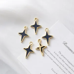 Detailed macro view of four-pointed star jewelry charms with gold plating and black enamel.