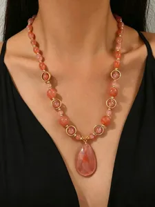 Close-up of dopamine style resin beaded necklace with large peach teardrop pendant