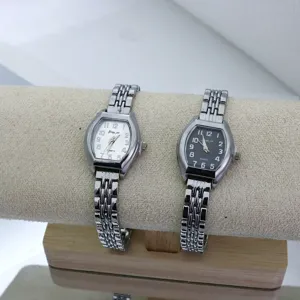 Detailed shot of women's tonneau quartz watch with metal link bracelet and dual dials.