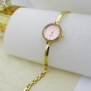 Close-up detail of women's gold quartz bracelet watch with pink dial and sparkling crystal bezel.