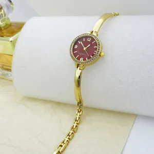 Detailed close-up of a women gold fashion bracelet quartz watch with striking red dial crystal bezel.