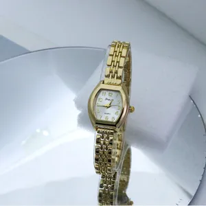 Gold tone tonneau quartz watch detail featuring a delicate link bracelet and elegant white dial.