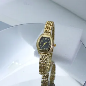 Gold tone tonneau quartz watch with black dial and delicate link bracelet detail view.