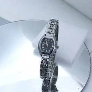 Close-up detail shot of silver-tone tonneau quartz watch featuring stylish linked bracelet.