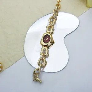 Detailaufnahme einer goldenen Quarzarmbanduhr mit unregelmäßiger Kette im Punk-Stil.