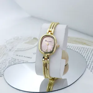 Reloj de cuarzo dorado para mujer con esfera ovalada rosa y pulsera de cadena multi hilos.