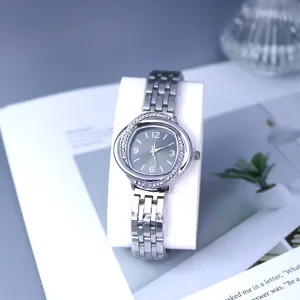 Crystal embellished bezel detail and silver steel strap of women quartz watch close up.