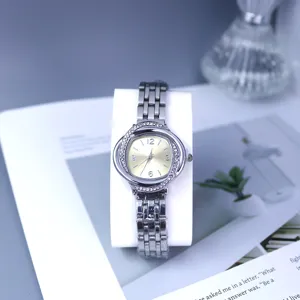 Detailed shot of a silver rhinestone women quartz watch with a golden dial and metal strap.