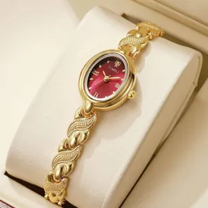 Détail de montre quartz ovale vintage, cadran rouge et bracelet texturé doré pour femme.