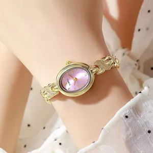 Montre quartz ovale élégante pour femme avec cadran rose et bracelet chaîne fin, détail rétro.