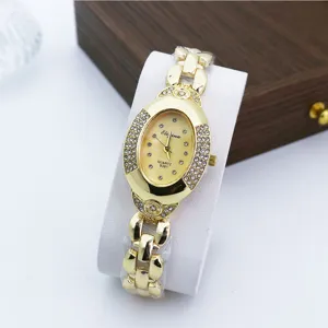 Primer plano de reloj de cuarzo ovalado vintage con estrás, pulsera de cadena dorada y cristales.