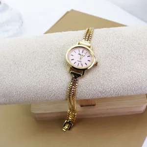Nahaufnahme einer goldenen Damen-Quarzuhr mit rosafarbenem Zifferblatt und filigranem Armband.