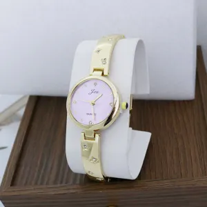 Vista de detalle de reloj de cuarzo para mujer con esfera morada y pulsera dorada.
