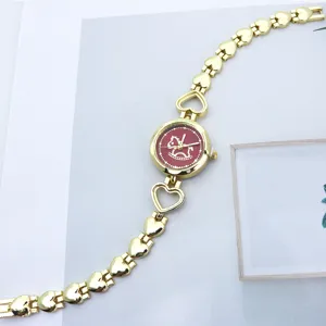 Detaillierte Nahaufnahme der goldenen Damenuhr mit Herzgliedern und rotem Zifferblatt.