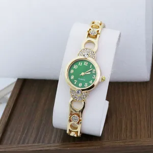 Close-up of a stylish gold women's watch with green dial and sparkling rhinestone details.