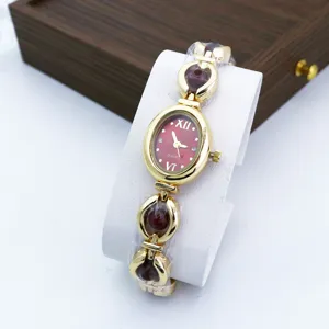 Chic women's quartz bracelet watch featuring an elegant red oval dial and stylish gold band.