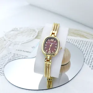 Exquisito detalle del pequeño reloj de cuarzo dorado con una fina correa de cadena.