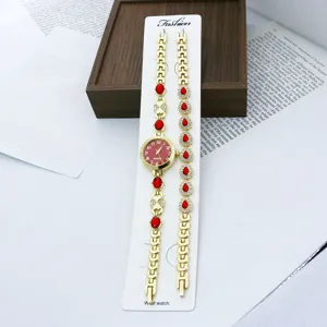 Goldfarbene Quarz-Modeuhr und Armband-Set Detailansicht mit roten Schmucksteinen verziert.