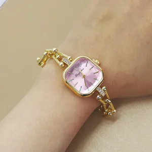 Nahaufnahme der goldenen Damen-Armbanduhr mit quadratischem Zifferblatt und Hufeisen.