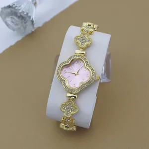 Vue detaillee d une montre femme strass trefle de luxe avec cadran rose et bracelet or.