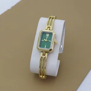 Detailed shot of gold bracelet watch with green rectangular dial and elegant metallic cuff.