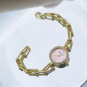 Goldene Damen Quarz Armbanduhr mit pinkem Zifferblatt, Strass Lünette und Kette Design.