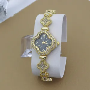 Détail montre strass trèfle, bracelet chaîne en métal doré avec pierres en cristal scintillantes.