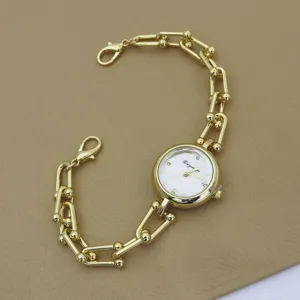 Detail view of a stylish gold-tone chain watch with unique link design and white dial.