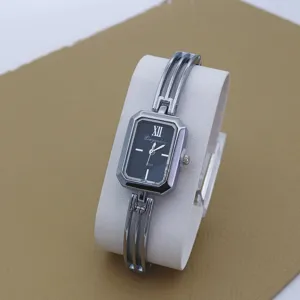 Detailed view of women's silver bracelet quartz watch with rectangular black dial and Roman numerals.