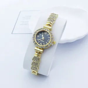 Detailaufnahme einer Damen Quarzarmbanduhr mit Strass Lünette und goldenem Gliederarmband.