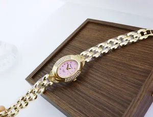 Reloj de cuarzo dorado para mujer con esfera ovalada de estrás rosa y cadena chic.