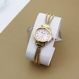 Detailansicht einer filigranen Damen-Quarzuhr mit goldener Kette und rosafarbenem Zifferblatt.