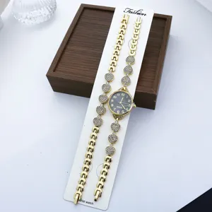 Damen Quarz Modeuhr Armband Set mit Strass Herz Details und goldener Metalloberfläche.