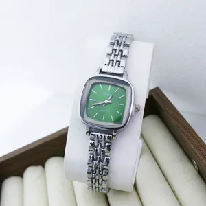 Détail de montre quartz carrée verte avec un magnifique bracelet en métal pour les femmes.