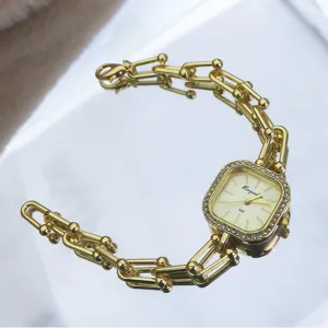 Detail view of a luxury square rhinestone quartz watch with gold chain bracelet style.