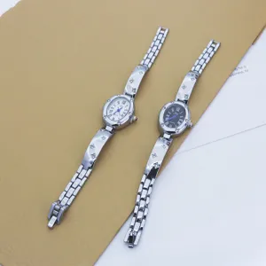Detailed view of women oval quartz watch with elegant Roman numerals and clover chain strap.