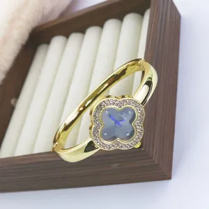 Detail shot of a luxury gold rhinestone four leaf clover bangle quartz watch in a display box.