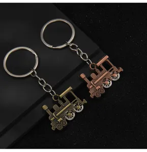 Close-up view of vintage steam locomotive keychains featuring movable wheels and metal rings.