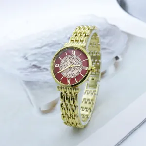Vista detallada del reloj de mujer dorado con esfera brillante de pedrería roja.