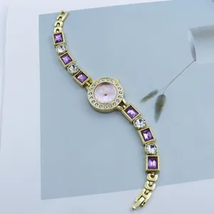 Women luxury quartz bracelet watch with purple crystal rhinestones and gold metal strap.