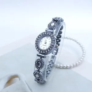 Nahaufnahme einer Damen Quarzarmbanduhr mit Strasssteinen, ovalem Zifferblatt und Gliederarmband.