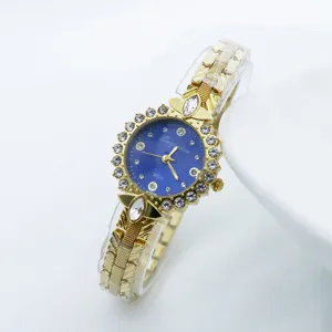 Vue rapprochée d'une montre quartz dorée avec cadran bleu et lunette sertie de strass.