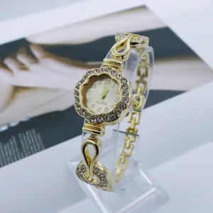Primer plano detallado de la esfera del reloj de cuarzo con flor de estrás dorada y correa.